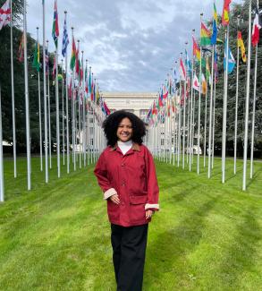 Picture of a woman wearing a red coat in front of the United Nations Building