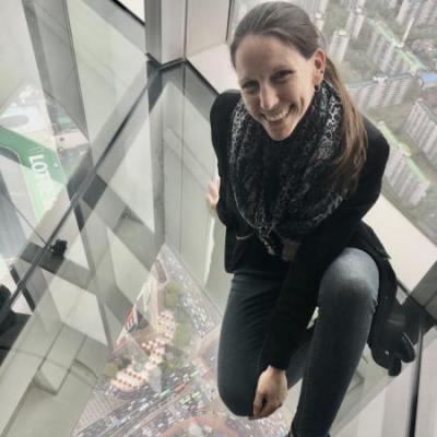 Photograph of Heather Fletcher sitting on the glass floor of a building in Seoul, South Korea.