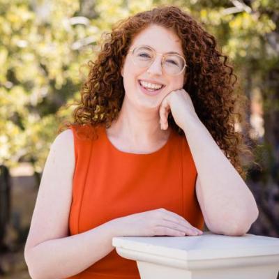 A redheaded woman in an orange dress smiling